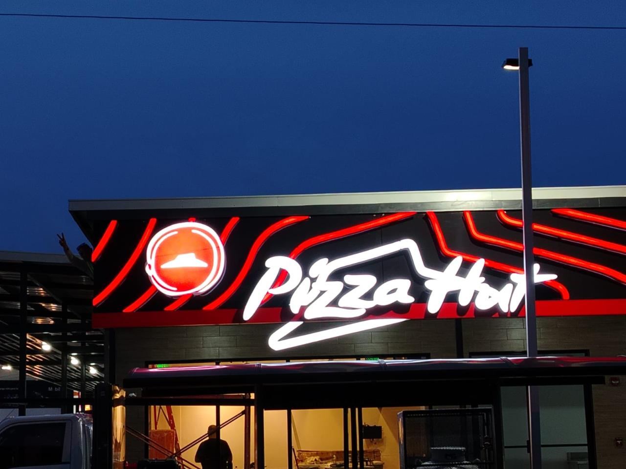 Rótulo de neón LED de Pizza Hut iluminado de noche en fachada, instalado por KROMA Impresiones
